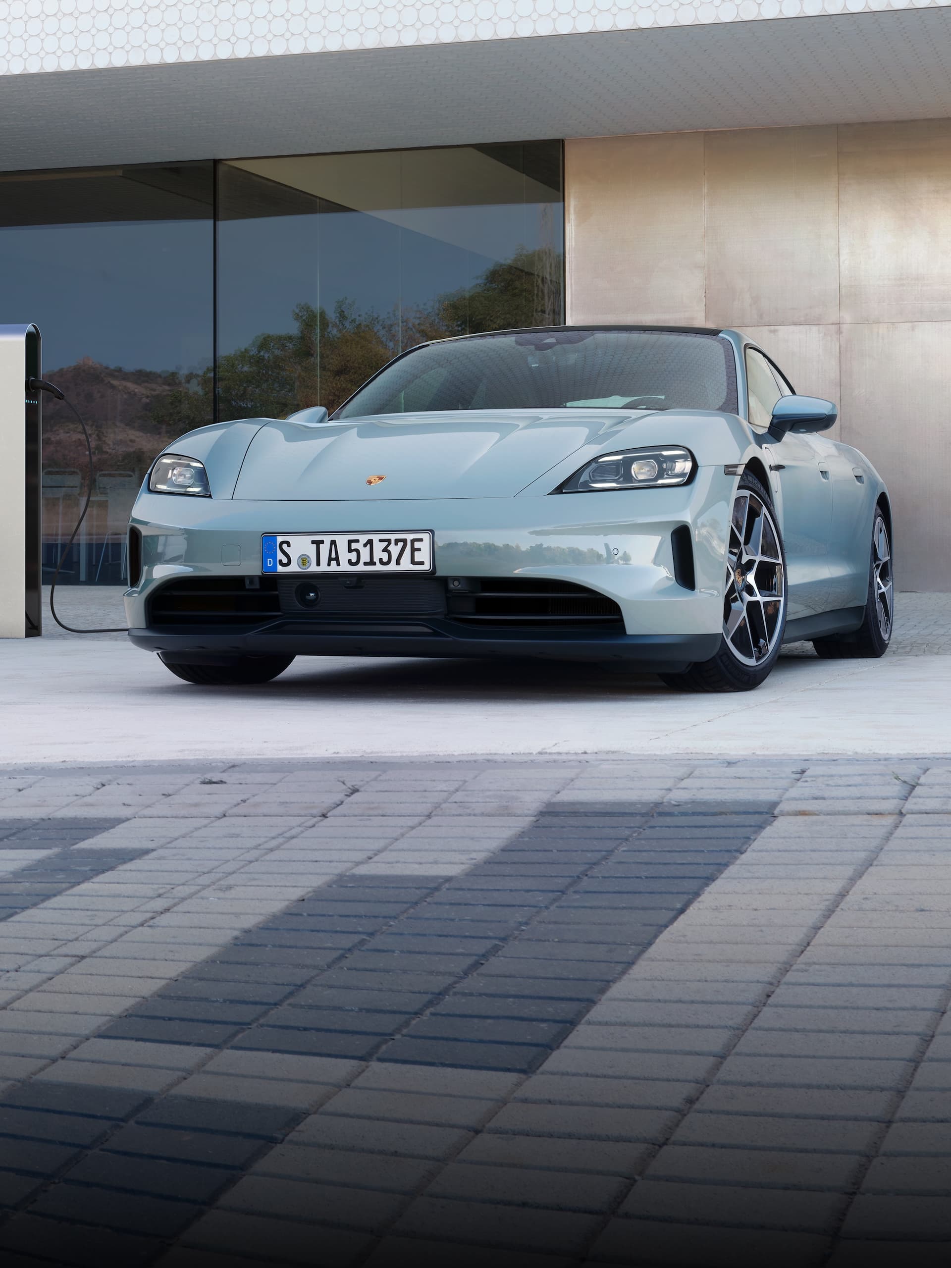 Une Porsche Taycan garée devant un immeuble moderne.